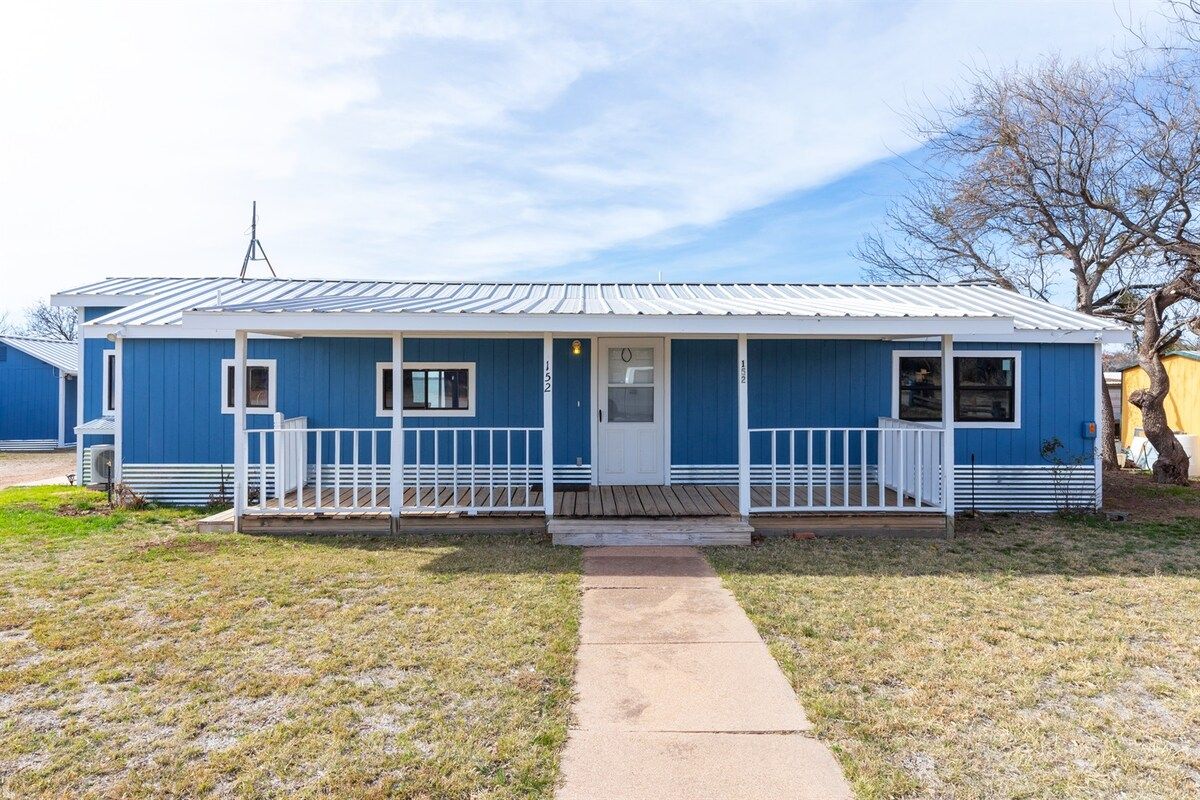 A single-story blue building with a white porch and a small front yard.