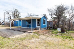 A blue single-story building with a covered porch and a small outdoor seating area. - Best Sunsets on the Lake! 2-Bed 1-Bath | Gameroom! (Abilene)