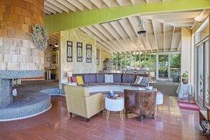 A spacious living area with a curved sectional sofa, a fireplace, and a large window providing a view of the outdoors. - Mountain View Hideaway (Seattle)