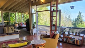 Un vaste espace de vie doté d’un plancher en bois, d’un fauteuil jaune, d’une table ronde en bois et d’une bibliothèque remplie de livres.