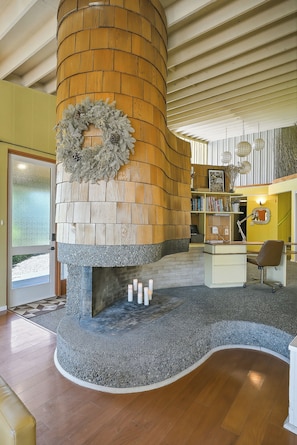 A fireplace with a stone surround, a wooden wall, and a bookshelf with books. - Mountain View Hideaway (Seattle)