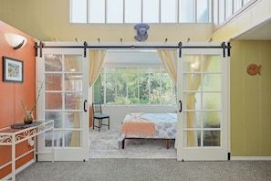 A room with a bed, a chair, a table with a vase, and a window with curtains. - Mountain View Hideaway (Seattle)
