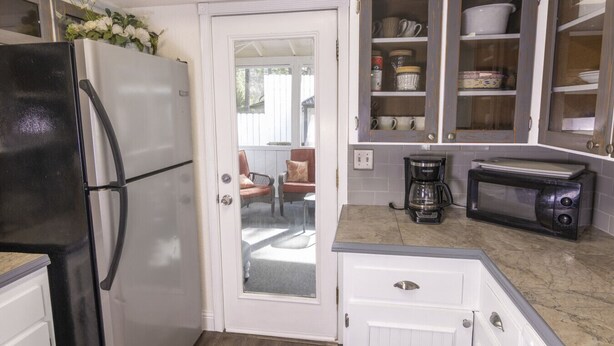 A compact kitchen with a refrigerator, coffee maker, microwave, and cabinets. - Near Bass Lake | Harley`s Hideaway Suite | Hot Tub (Oakhurst)