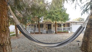 A hammock between trees in a backyard with a house in the background. - Near Bass Lake | Harley`s Hideaway Suite | Hot Tub (Oakhurst)