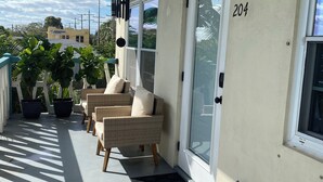 Ein überdachter Balkon mit Korbmöbeln, Topfpflanzen und einer Tür mit der Nummer 204.