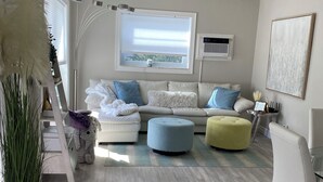 Ein modernes Wohnzimmer mit einer Couch, Poufs, einer Leiter und einem Blumentopf.