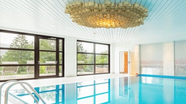 Ein Pool mit modernem Design, großen Fenstern und einer einzigartigen Deckenleuchte.