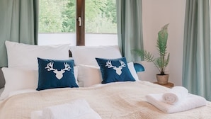 Ein Bett mit weißen und blauen Kissen, einer weißen Decke und einem aufgerollten weißen Handtuch.