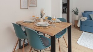 Ein Essbereich mit einem Holztisch, gedeckten Plätzen für vier Personen, stuhlfarbenen Stühlen und gerahmten Bildern an der Wand.
