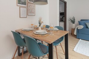 A dining area with a wooden table set for four, teal chairs, and framed artwork on the wall. - Cozy Bergzeit 230: Mountain view | Families | Stylish (Bad Goisern am Hallstättersee)