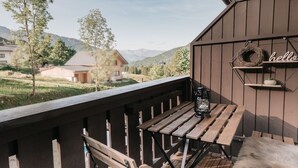 Eine Holzterrasse mit Tisch und Stühlen, einer Laterne und einem Schild mit dem Aufschrift 'hello' an einem Gebäude.