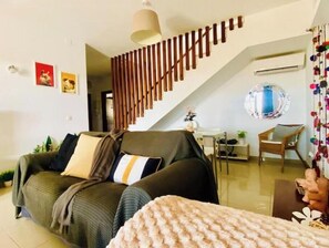 A modern living room with a sofa, a coffee table, and a staircase. - Villa Nillos (Playa Blanca)