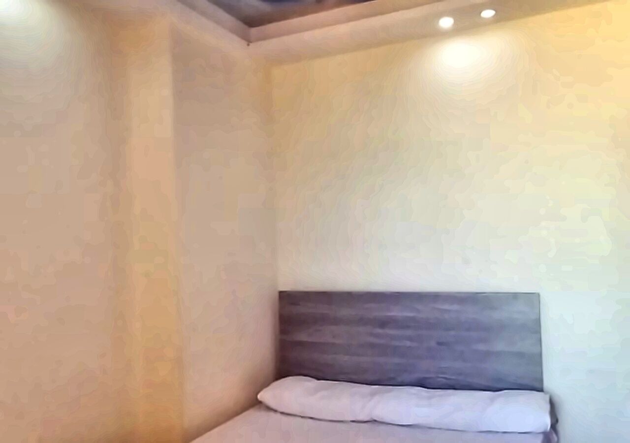 Ein Schlafzimmer mit Bett, Kopfteil und Einbaustrahlern.