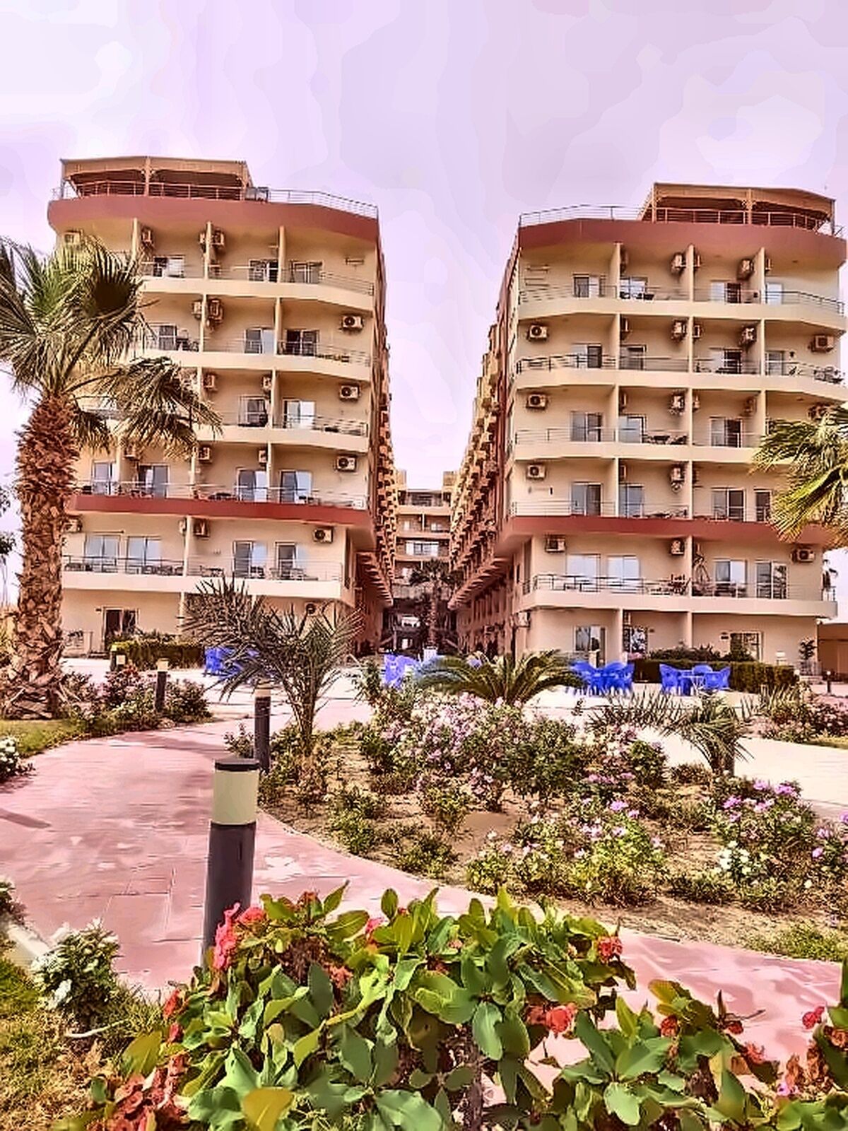 A multi-story hotel with balconies, a central courtyard, and surrounding greenery.