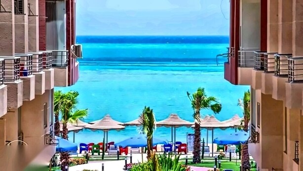 A hotel balcony with a view of the ocean, outdoor seating, and palm trees. - Your perfect Red Sea getaway at Hurghada. (Hurghada)