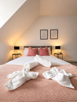 A neatly made bed with a checkered pillow, two bedside lamps, and artwork on the wall. - Garden Relaxation, Easy City Centre Access, Secure Parking, Groups & Families (Nottingham)