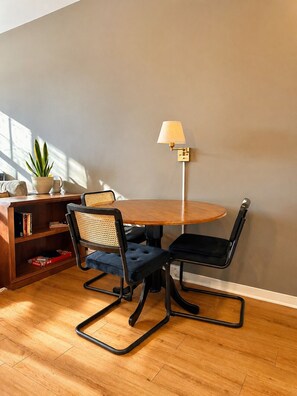 A dining area with a round table, two chairs, a floor lamp, a bookshelf, and a potted plant. - Walker`s Point Designer 2BR · Prime Location with Balcony and Gym · Sleeps 6 (Milwaukee)