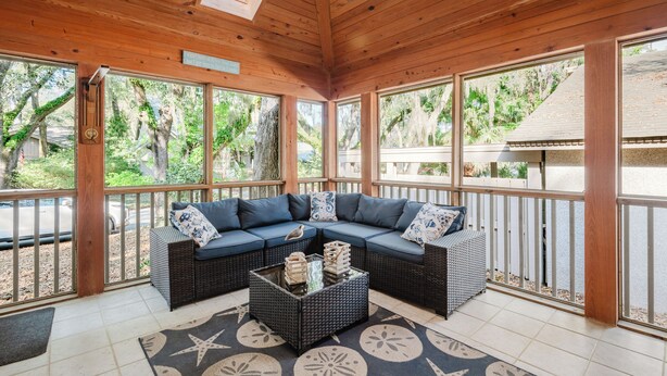 A covered outdoor seating area with a sectional sofa, a coffee table, and a view of the surrounding greenery. - Sea Pines Serenity w/pool access & beach shuttle (Hilton Head Island)