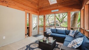 A wooden interior with a sofa, a coffee table, and large windows. - Sea Pines Serenity w/pool access & beach shuttle (Hilton Head Island)