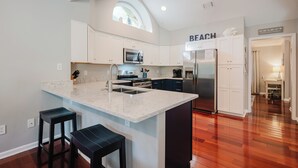 A modern kitchen with white cabinets, a large island, and a view of the beach. - Sea Pines Serenity w/pool access & beach shuttle (Hilton Head Island)