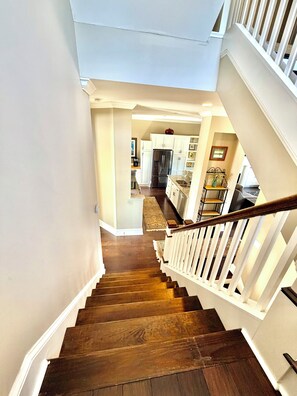 A staircase leading to a kitchen with white cabinets and a stainless steel refrigerator. - Marvelous 3-bedroom townhome with Pool, Boat Ramp and River Views (St. Marys)