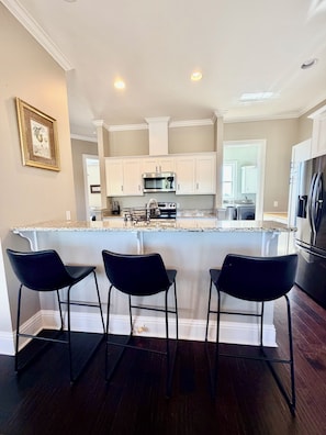 A kitchen with white cabinets, a stainless steel refrigerator, and a granite countertop. - Marvelous 3-bedroom townhome with Pool, Boat Ramp and River Views (St. Marys)