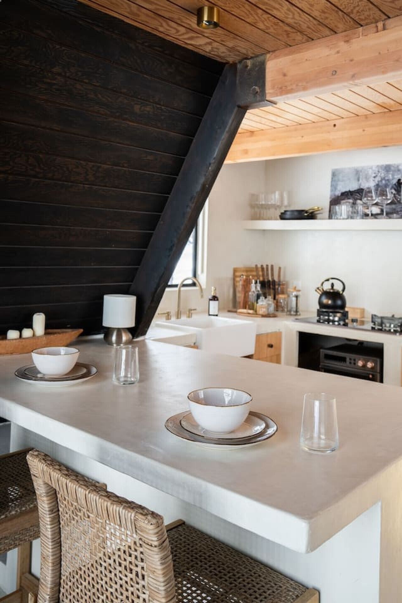 Une cuisine moderne dotée d’un îlot central, d’un four encastré et d’un porte-ustensiles suspendu.