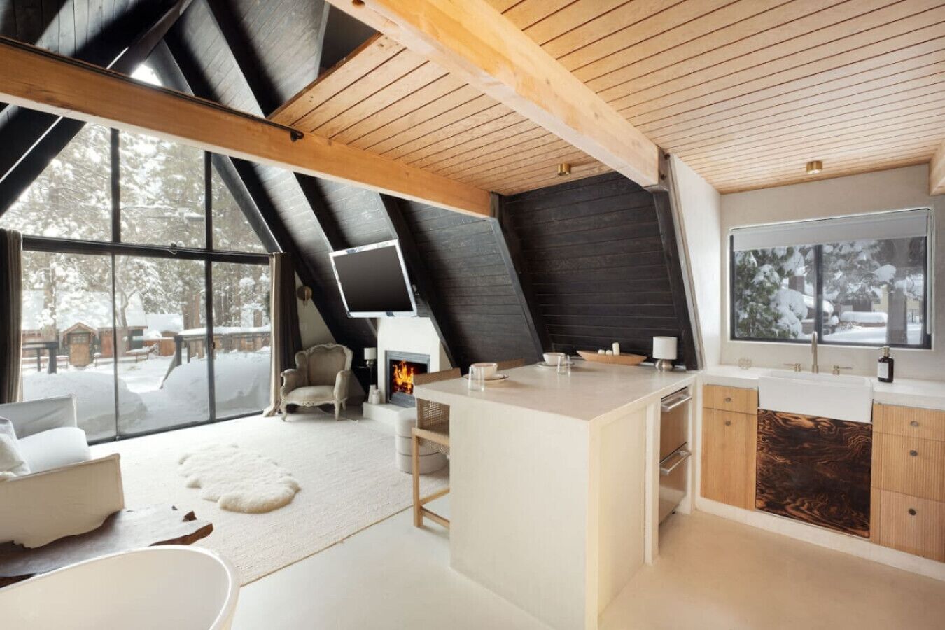 Un intérieur moderne avec une grande fenêtre, une cheminée et un coin cuisine.