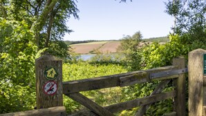 A wooden gate with a sign indicating a hiking trail and a no cycling or dog area. - Charming Riverside Cottage in the Heart of Pembrokeshire (Cosheston)