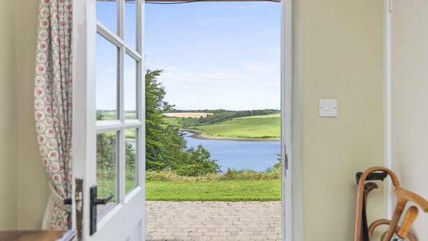 An open door leading to a view of a lake and greenery. - Charming Riverside Cottage in the Heart of Pembrokeshire (Cosheston)