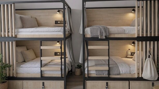 Two bunk beds with storage compartments, a small bedside table, a lamp, and a plant. - Mixed Dorm 8 - 1 Bed (Berlin Sleep Club) (Berlin)