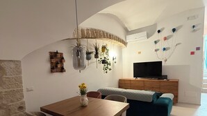Een moderne woonkamer met een eethoek, een televisie en een stenen muur.