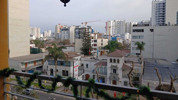 A balcony with a view of a cityscape, including buildings and a construction crane. - Apartamento Ideal en Zona Centrica (Jesús María)