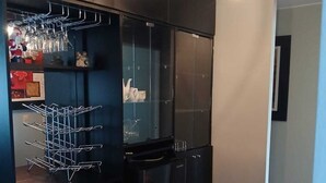 A modern kitchen with black cabinetry, a wine rack, and hanging lights. - Apartamento Ideal en Zona Centrica (Jesús María)
