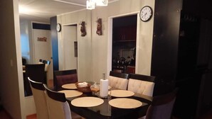 A dining area with a black table, beige upholstered chairs, and a clock on the wall. - Apartamento Ideal en Zona Centrica (Jesús María)