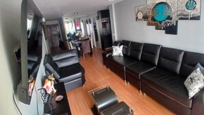 A living room with a sofa, a coffee table, a TV, and a wall art piece. - Apartamento Ideal en Zona Centrica (Jesús María)