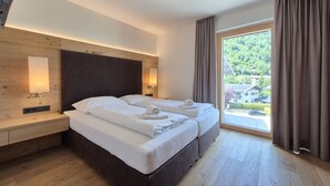 Ein modernes Hotelzimmer mit einem großen Bett, Nachttischen, einer Wandlampe und Blick auf Grünflächen.