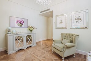 A room with a white console table, a green armchair, and framed floral artwork on the wall. - Deluxe Junior Suite with Terrace & Balcony in Sorrento Center (Sorrento)