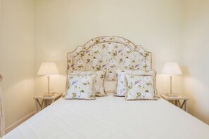 A neatly made bed with floral headboard and matching pillows, two bedside lamps, and a small bedside table. - Deluxe Junior Suite with Terrace & Balcony in Sorrento Center (Sorrento)