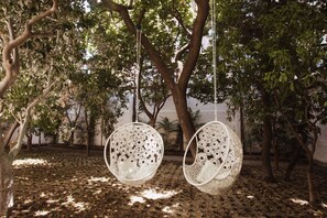 Two intricately designed hanging chairs suspended from a tree in an outdoor setting. - Deluxe Junior Suite with Terrace & Balcony in Sorrento Center (Sorrento)
