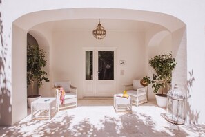 A white-walled room with a door, two wicker chairs, a small table, and potted plants. - Deluxe Junior Suite with Terrace & Balcony in Sorrento Center (Sorrento)