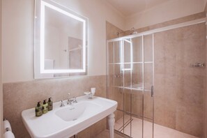 Een badkamer met een witte wastafel, een grote spiegel en een douche met glazen wanden.