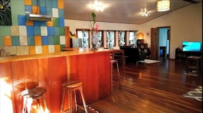 A bar area with stools, a counter, and a decorative vase with flowers. - Roots and Wings Spacious House With Forest Views and Private Garden (Monteverde)