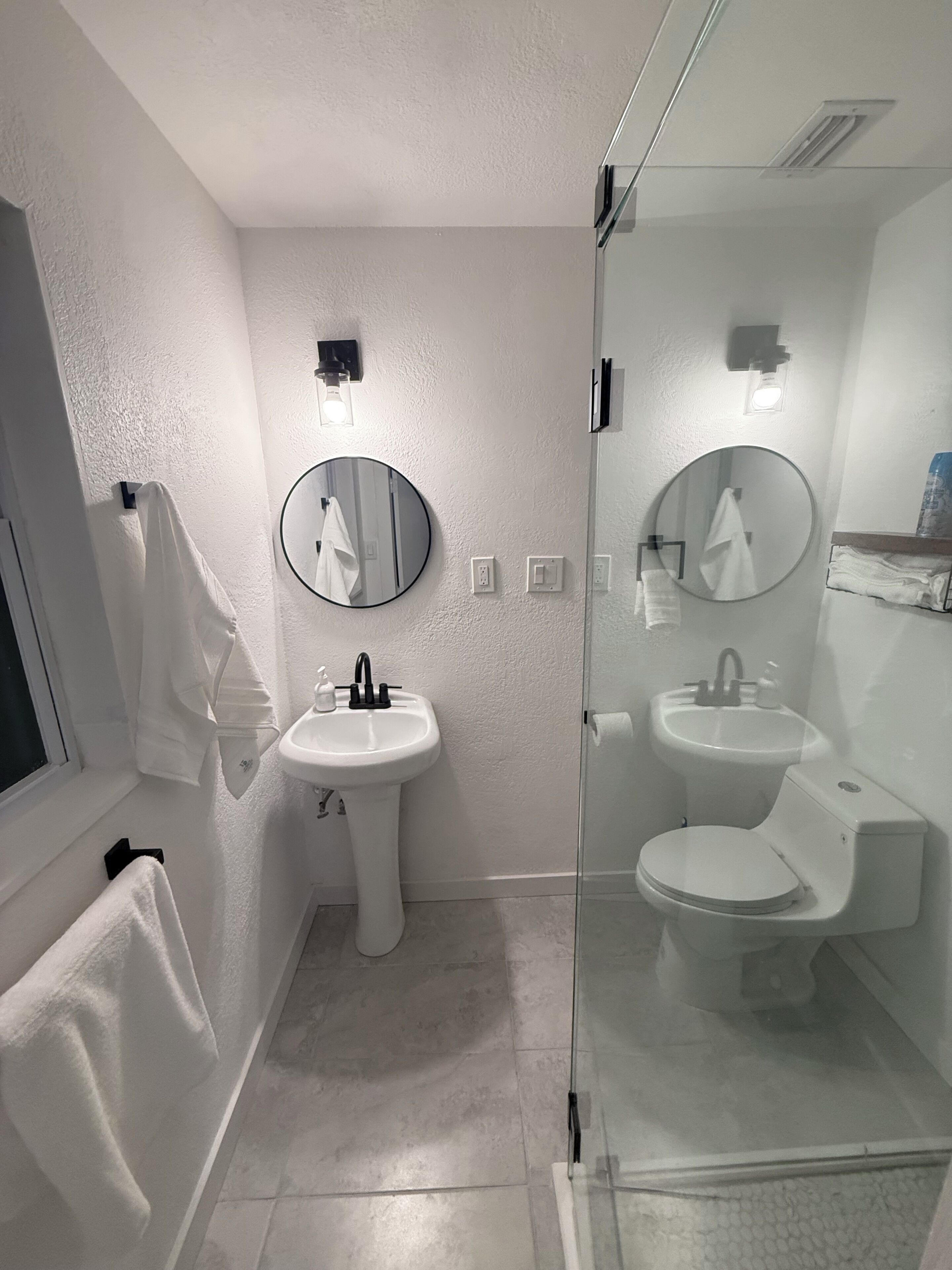 Un bagno con due lavandini, un water e una cabina doccia in vetro.