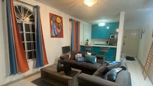 Een woonkamer met een bank, een salontafel en een eethoek, met een keuken op de achtergrond.