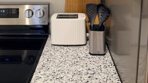Una cocina con microondas, tostadora y cristalería sobre la encimera.