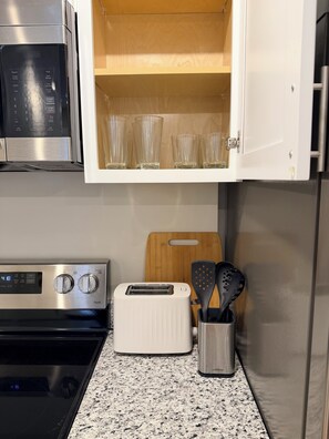 Eine Küche mit einer Mikrowelle, einem Toaster und Glaswaren auf der Arbeitsplatte.