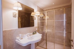 A bathroom with a white sink, gold fixtures, and a glass shower enclosure. - Executive Suite with Terrace in Sorrento Center (Sorrento)