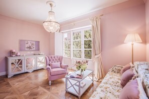 A pink-themed living room with a chandelier, a sofa, a chair, a coffee table, and a cabinet. - Executive Suite with Terrace in Sorrento Center (Sorrento)