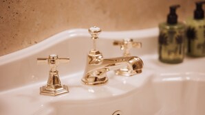 A bathroom sink with two gold faucets and two green bottles in the background. - Executive Suite with Terrace in Sorrento Center (Sorrento)